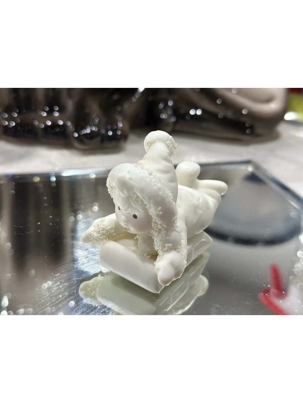 Department 56 Snowbabies figurine shows a baby dressed in a snowsuit playing